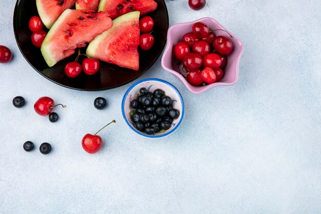 Top view copy space slices of watermelon on a plate with blueberries and cherries