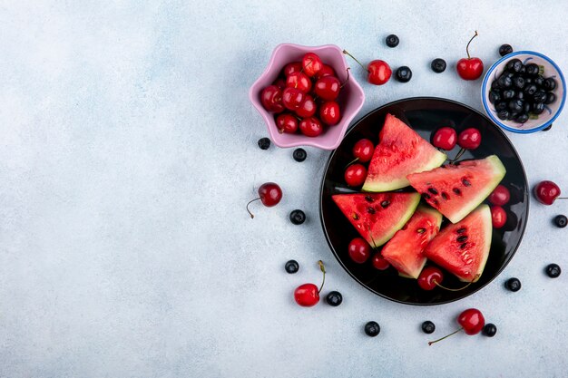 Top view copy space slices of watermelon on a plate with blueberries and cherries