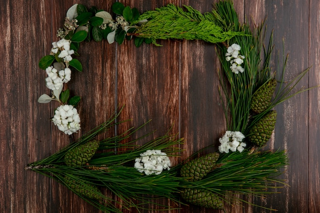 Free Photo top view copy space spruce branch with cones with white flowers around the edges on a wooden background