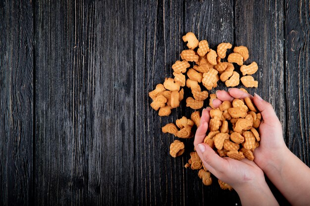 Top view copy space woman holds cookies on a black wooden background