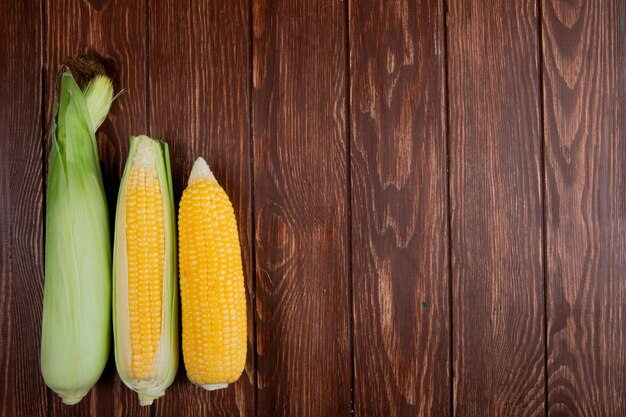 Top view of corn cobs with shell on left side and wood with copy space