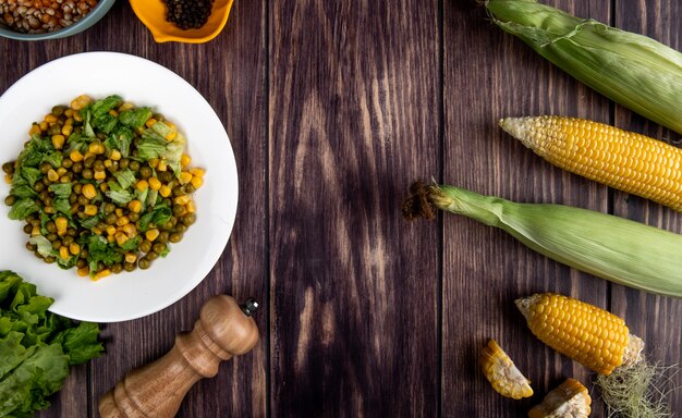 Top view of corn salad with cut and whole corns lettuce on wooden surface