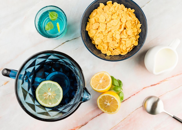 Free photo top view cornflakes with yogurt and lemon water