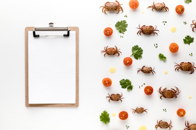 Top view of crabs and tomatoes with notepad