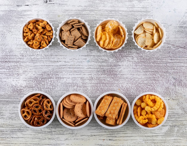 Free photo top view crackers in bowls with copy space on white wooden  horizontal