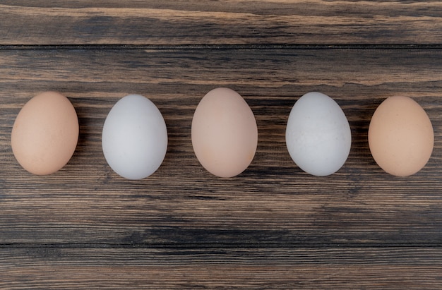 Free photo top view of cream and white colored chicken eggs on a wooden background