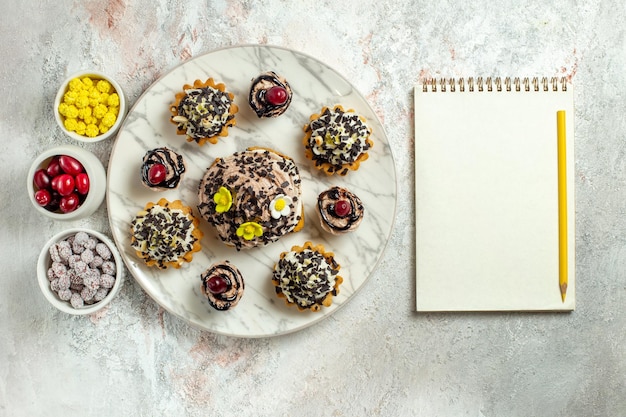 Free Photo top view creamy delicious cakes with candies on white desk tea cake biscuit sweet birthday cream