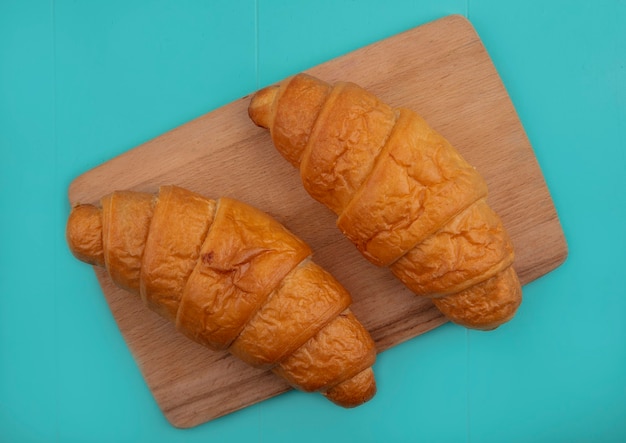 Free photo top view of croissants on cutting board on blue background