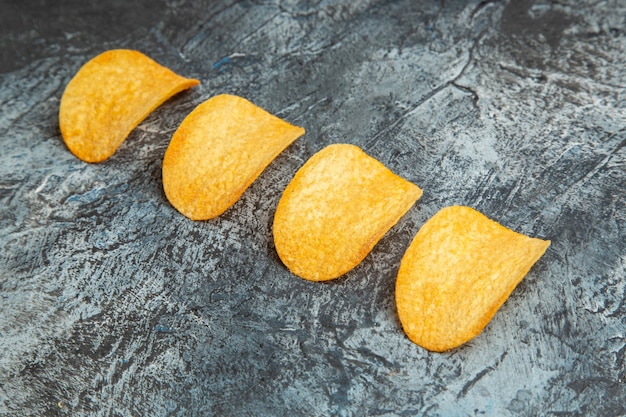 Top view of crunchy baked chips lined up in a row on gray background