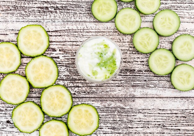 Top view cucumber sliced with white yogurt in glass bowl on white wooden  horizontal