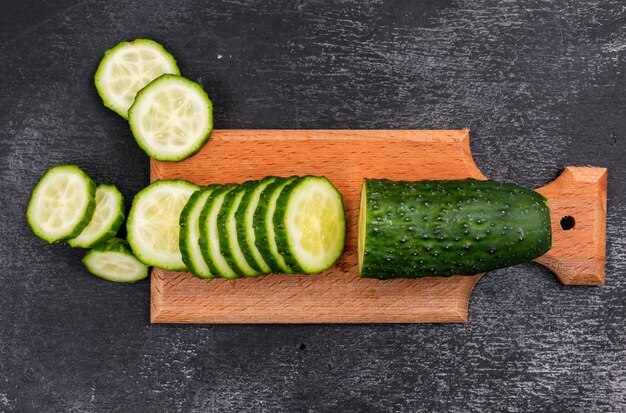 Top view cucumber sliced on wooden cutting board on black stone  horizontal