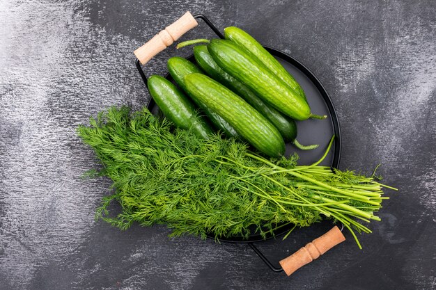 Top view cucumber with dill on black metal tray on black stone  horizontal