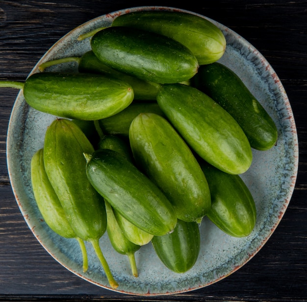 Free photo top view of cucumbers in plate on wood