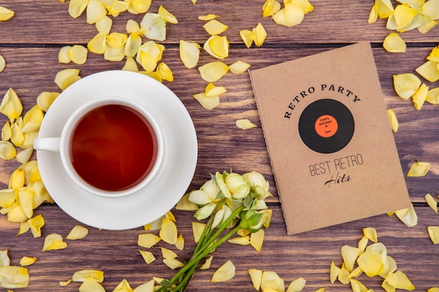 Top view of a cup of black and tasty tea with yellow petals isolated on wood