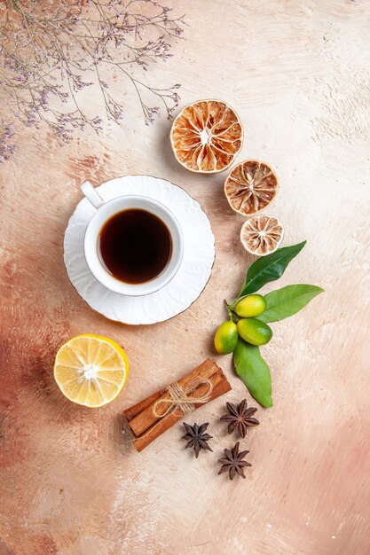 Top view of a cup of black tea with lemons and cinnamon sticks