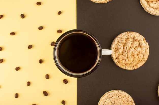 A top view cup of coffee with brown coffee seeds and crackers