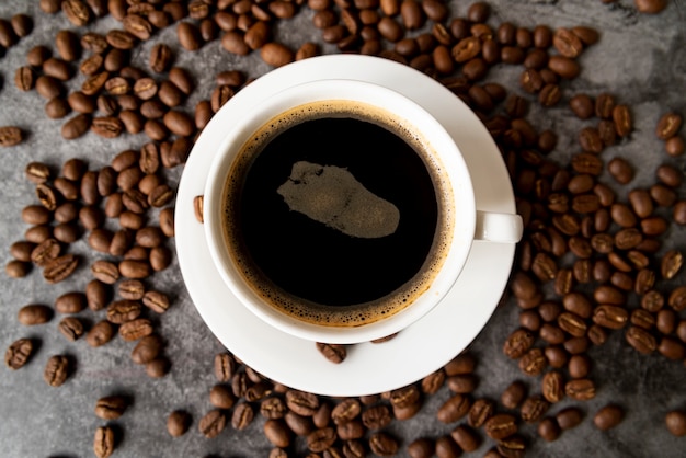 Free photo top view cup of coffee with roasted beans