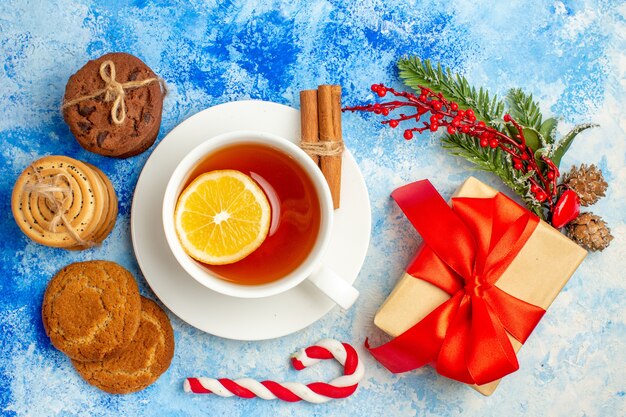 Top view cup of tea cookies tied up with rope giftbox on blue table