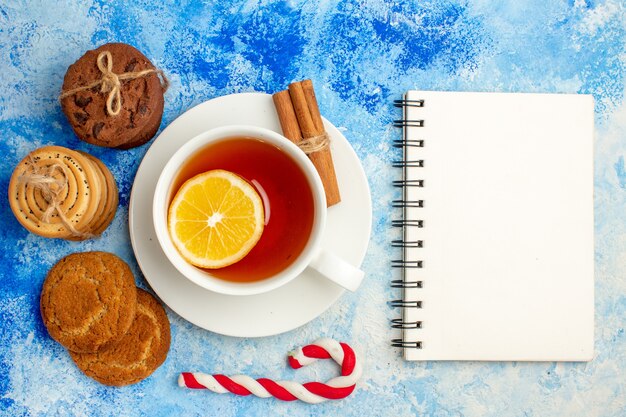 Top view cup of tea cookies tied up with rope notepad on blue table