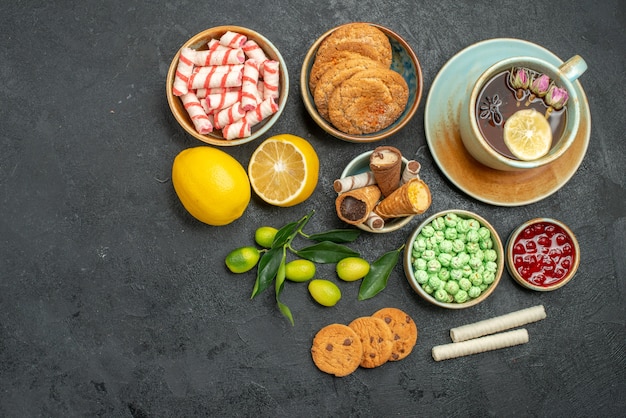 Top view a cup of tea a cup of herbal tea citrus fruits sweets cookies jam