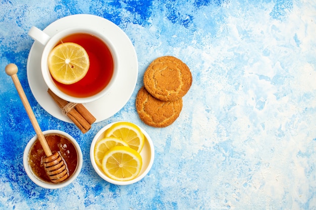 Free photo top view cup of tea honey in bowl biscuits lemon slices on blue table free space