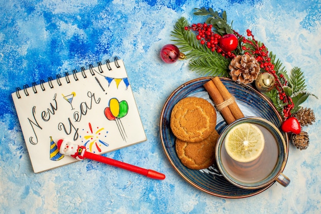 Top view cup of tea lemon slices in bowl cinnamon sticks tea in bowl on purple tablecloth notepad on dark red table