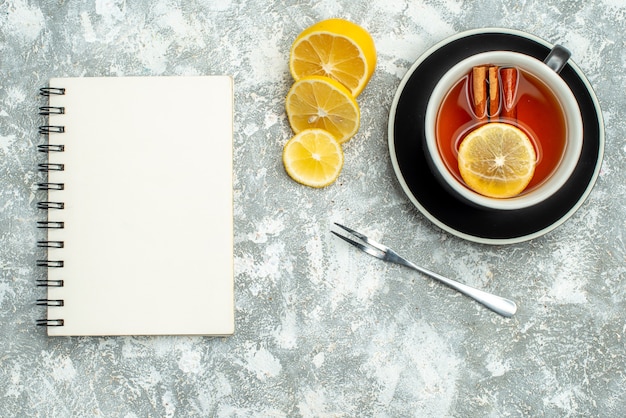 Top view a cup of tea lemon slices notebook on grey surface free space