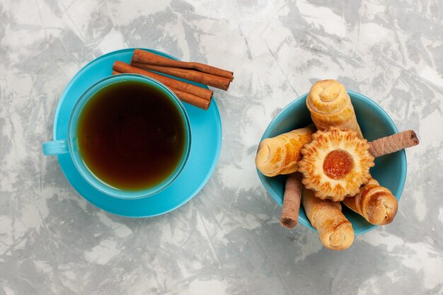 Top view cup of tea with bagels and cinnamon on white surface