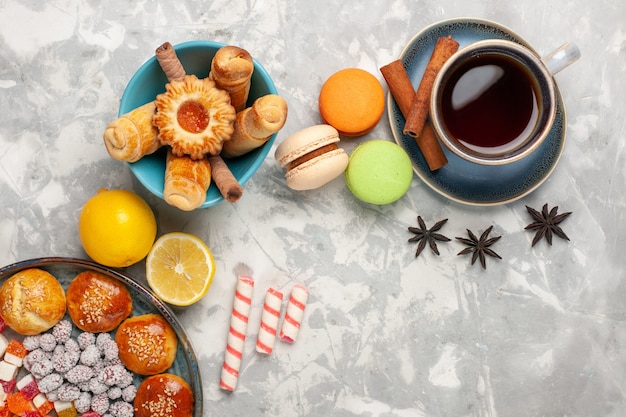 Free photo top view cup of tea with cakes and macarons on white surface