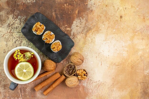 Top view cup of tea with cinnamon and confitures on light desk