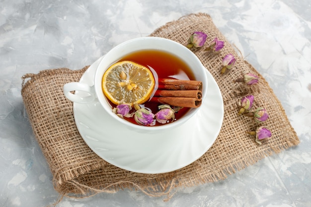 Top view cup of tea with cinnamon and lemon on light-white surface