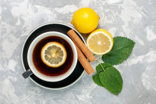 Top view cup of tea with cinnamon and lemon on light white surface