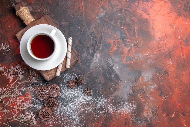 Top view cup of tea with cookies on dark table