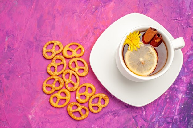 Top view cup of tea with crackers on pink table candy color lemon tea