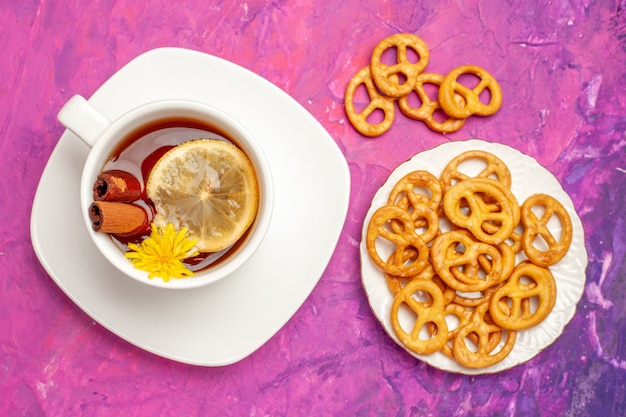 Free photo top view cup of tea with crackers on pink table color lemon candy tea