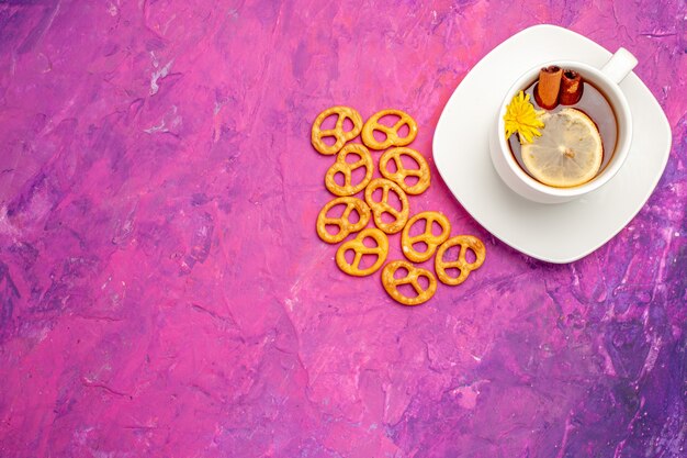 Top view cup of tea with crackers on pink table lemon candy color tea