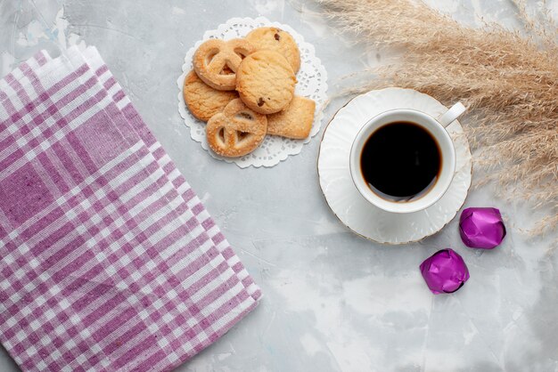 Top view of cup of tea with delicious little cookies chocolate candies on light, cookie biscuit sweet sugar