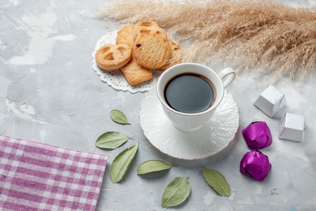 Top view of cup of tea with delicious little cookies chocolate candies on light desk, cookie biscuit sweet tea sugar