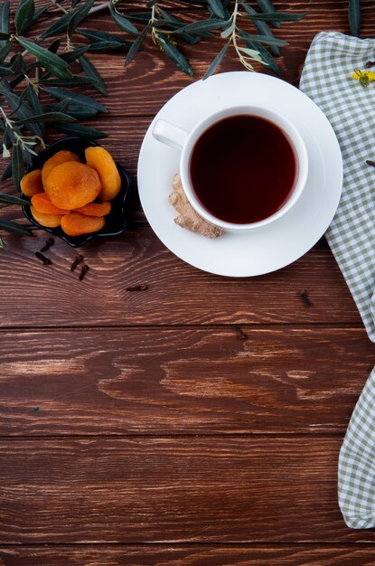 Top view of a cup of tea with dried apricots on wood with copy space