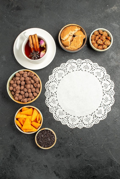 Free photo top view cup of tea with flakes and nuts on grey surface tea candy color