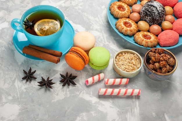 Free photo top view cup of tea with french macarons cookies and cakes on the white surface