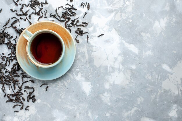 Top view cup of tea with fresh dried tea grains on the light table, tea drink breakfast