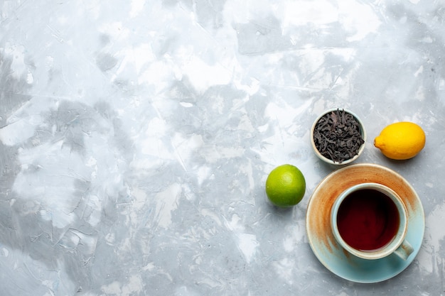 Top view cup of tea with fresh lemons and dried tea on the light table, tea fruit citrus color drink