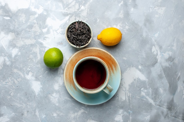 Top view cup of tea with fresh lemons and dried tea on the light table, tea fruit citrus color