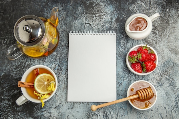 Free photo top view cup of tea with honey and fruits on light surface sweet fruit tea