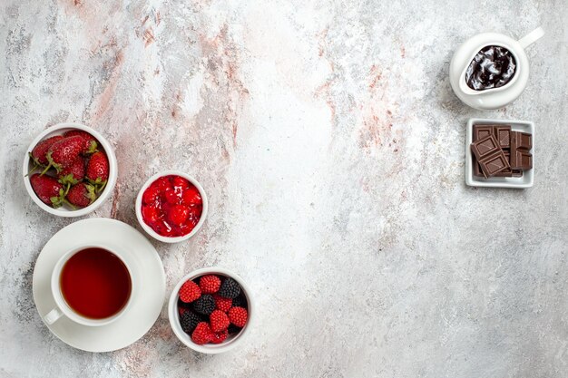 Top view of cup of tea with jam confitures and chocolate on a white surface