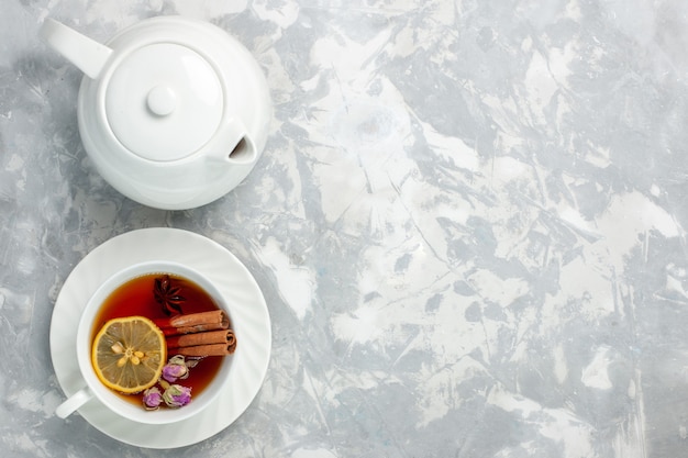 Free photo top view cup of tea with lemon and cinnamon on light white surface