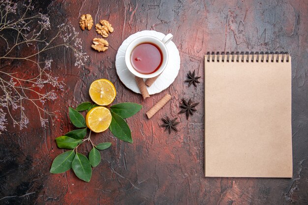 Top view cup of tea with lemon on dark table tea fruits dark photo