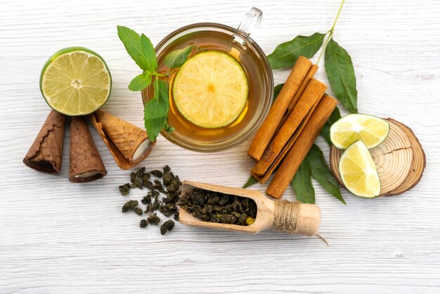 Free Photo a top view cup of tea with lemon mint and cinnamon on white, tea dessert candy