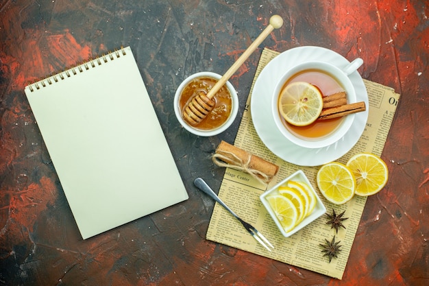 Free photo top view cup of tea with lemon slices in small bowl on dark red table